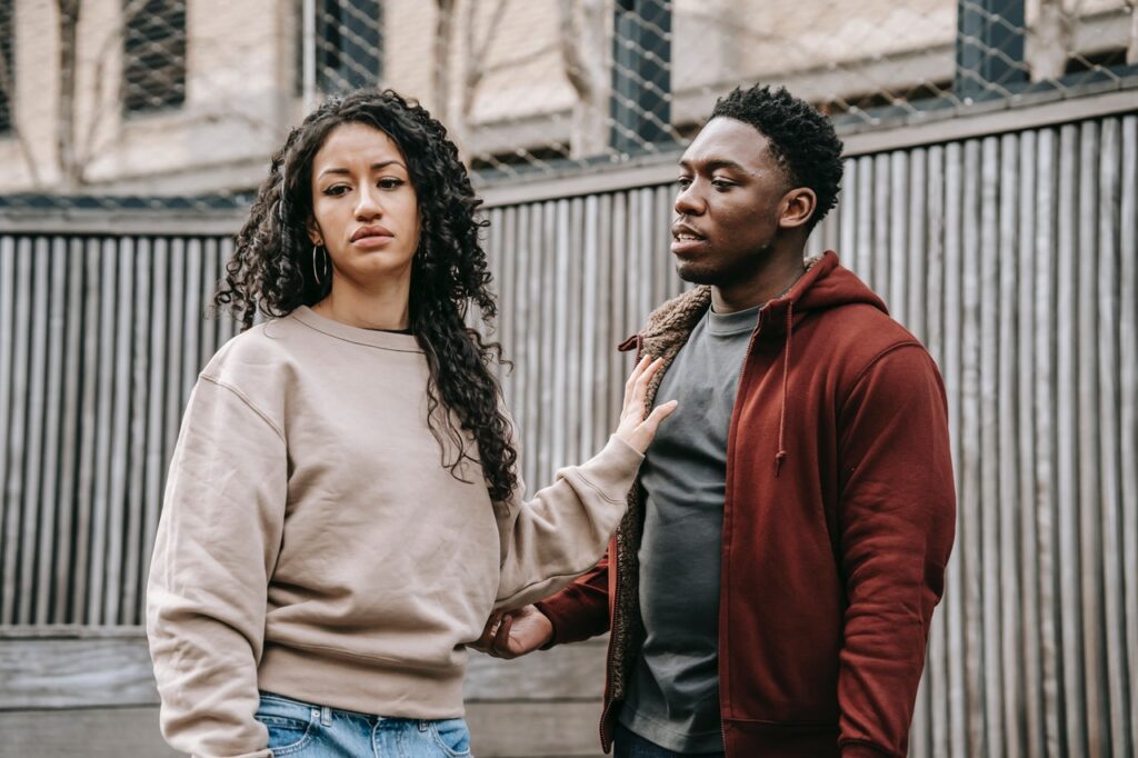 woman and man arguing in front of a fence